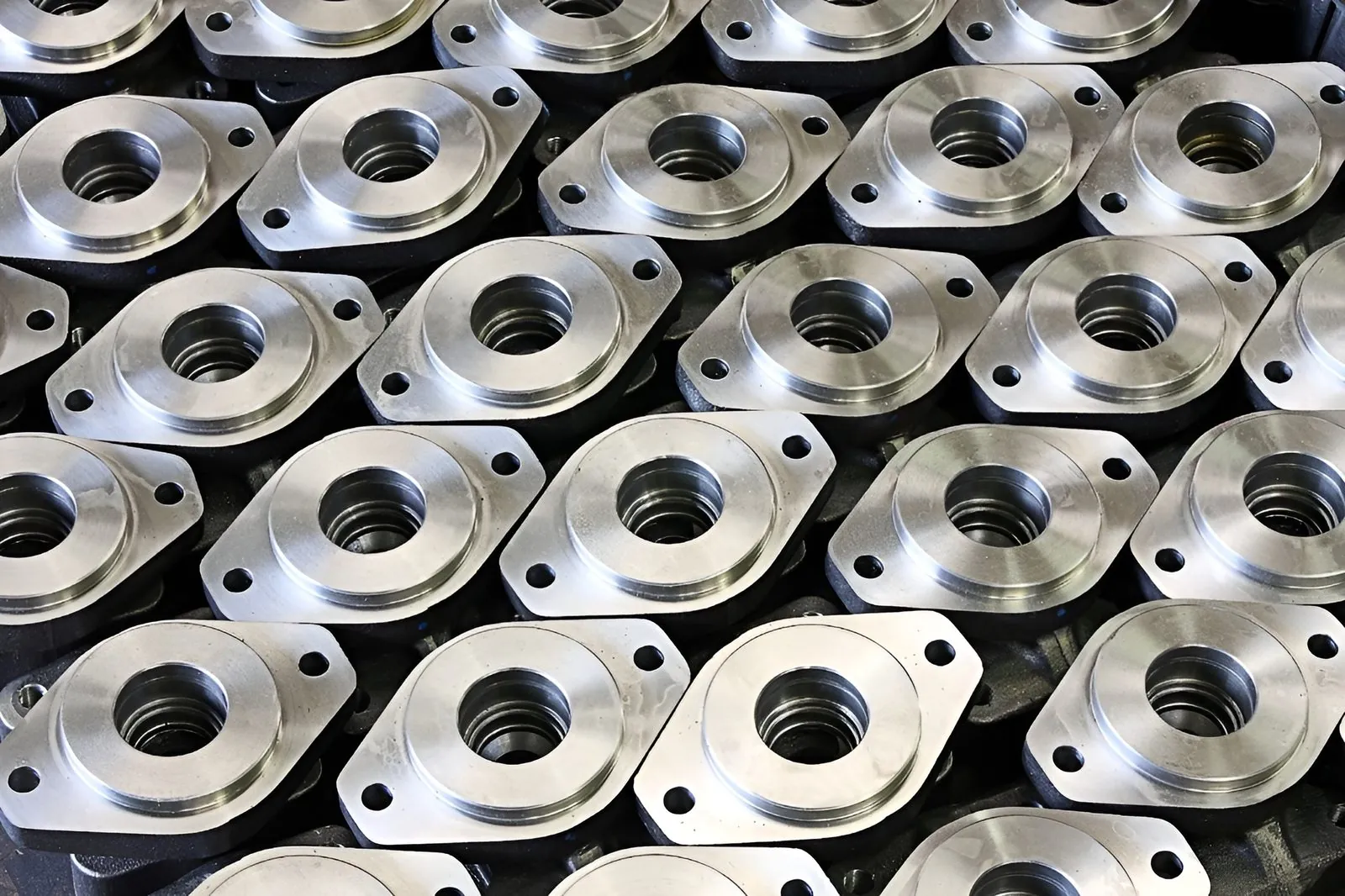 Rows of identical precision-machined metal flanges from a low-volume production run